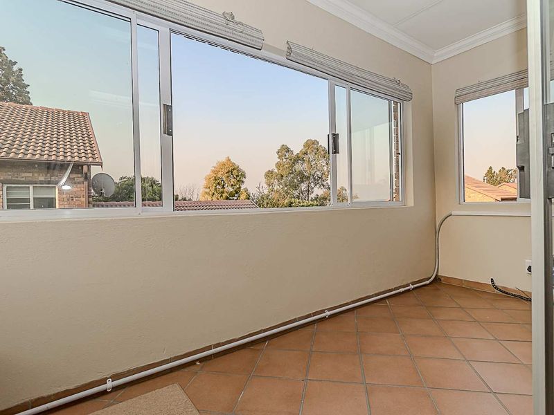 A sunroom or enclosed balcony featuring tiled flooring, large sliding windows, and crown molding, offering a bright and versatile space.