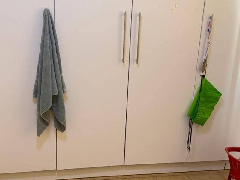 A bedroom featuring white built-in cupboards with modern handles and neutral tiled flooring.