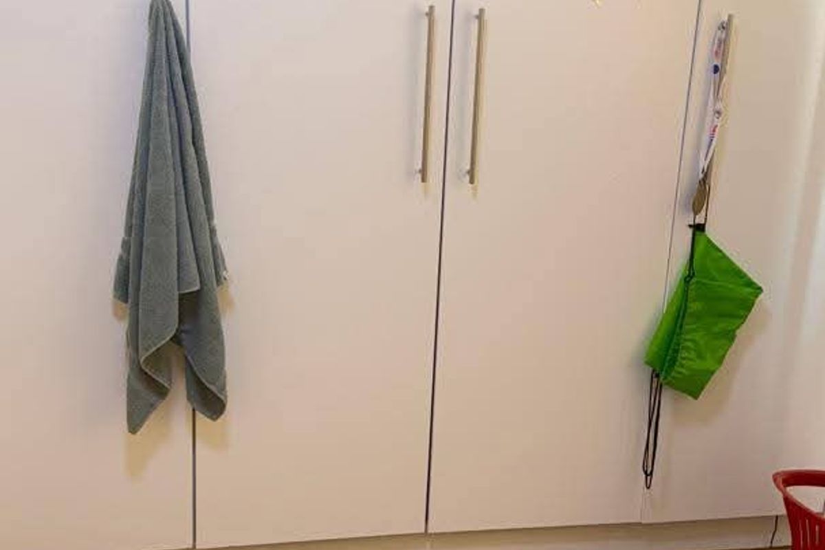 A bedroom featuring white built-in cupboards with modern handles and neutral tiled flooring.