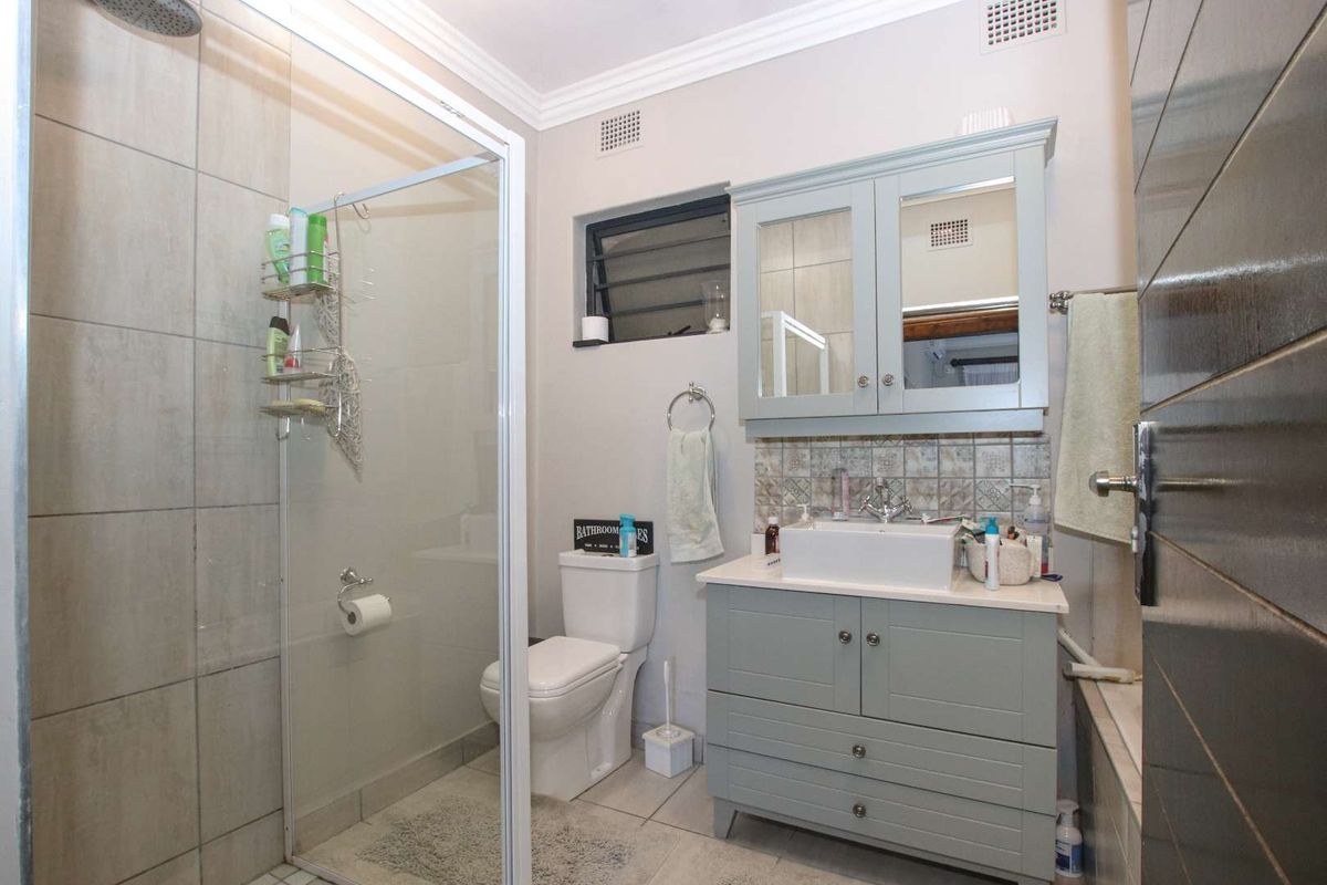 A well-maintained bathroom featuring a glass-enclosed shower, a modern vanity with a vessel sink, and a wall-mounted medicine cabinet.
