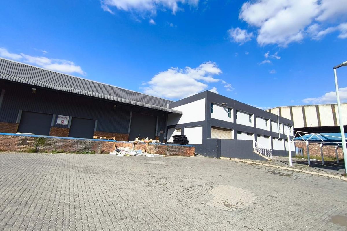 Industrial property exterior featuring a paved yard, loading bay with roller shutter doors, and multi-level office or storage structure.