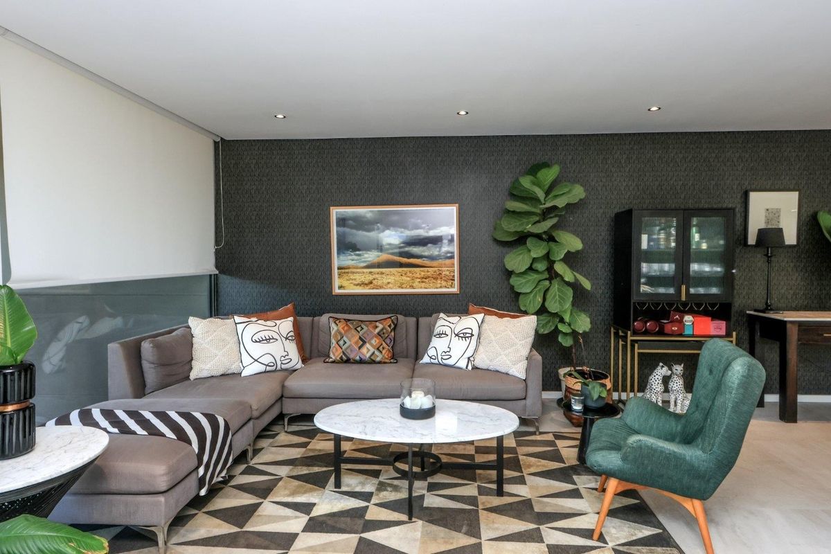 A well-appointed living room featuring a dark accent wall, recessed downlighting, and modern roller blinds, creating a sophisticated and comfortable atmosphere.