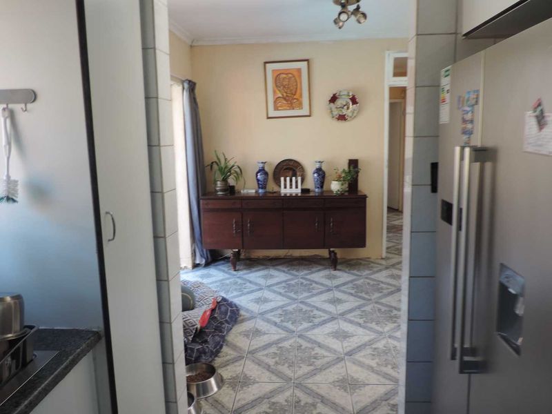 A view from the kitchen looking into an adjacent living area, featuring tiled flooring and neutral wall finishes.