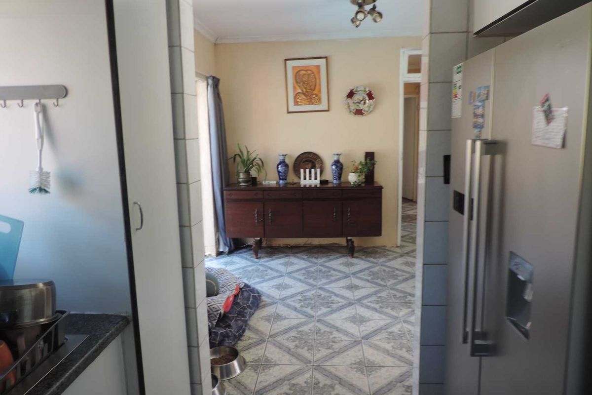 A view from the kitchen looking into an adjacent living area, featuring tiled flooring and neutral wall finishes.