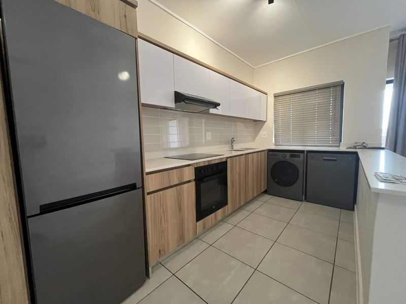 Modern kitchen featuring wood-grain and white cabinetry, stone countertops, integrated appliances, subway tile backsplash, and neutral tiled flooring.