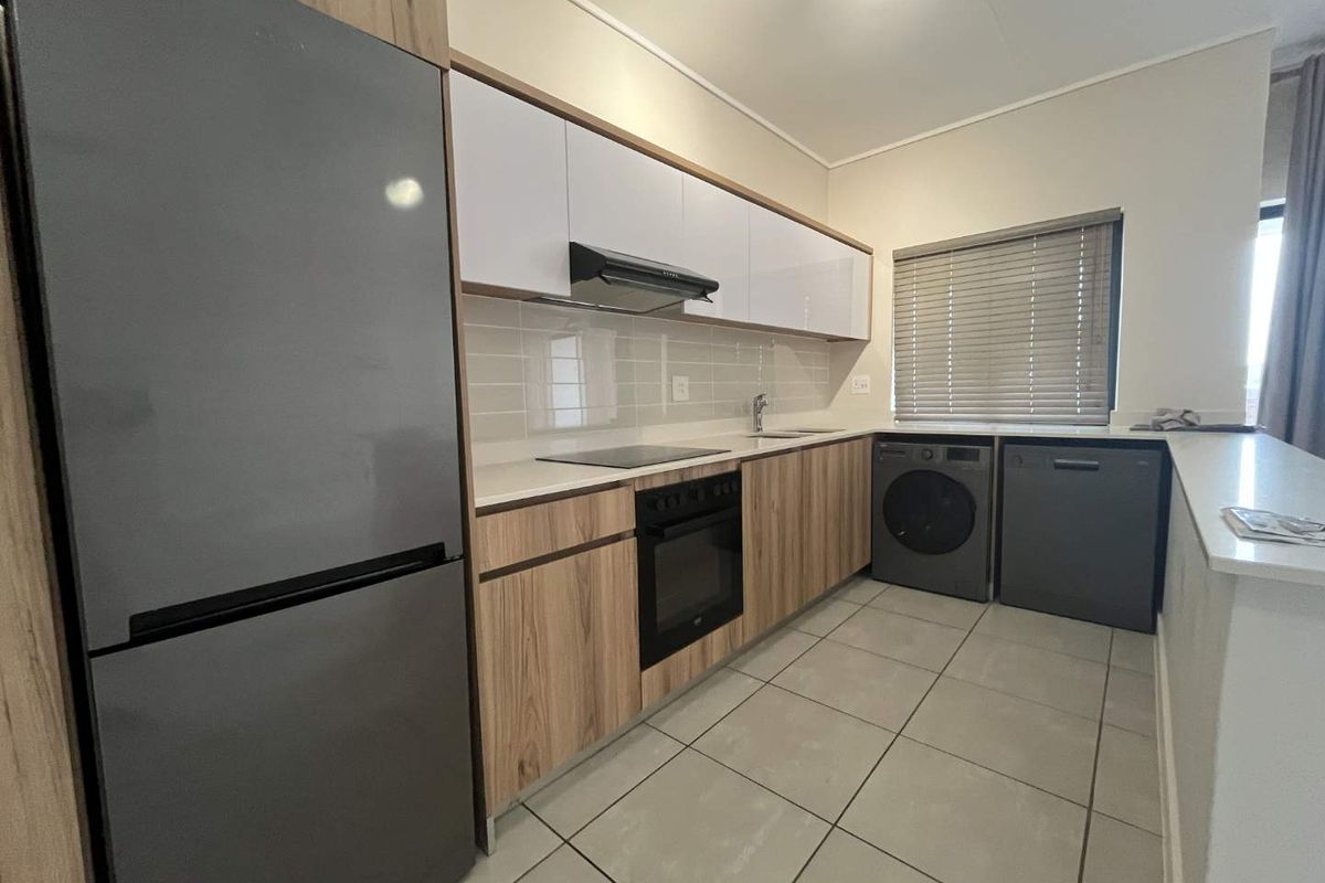 Modern kitchen featuring wood-grain and white cabinetry, stone countertops, integrated appliances, subway tile backsplash, and neutral tiled flooring.