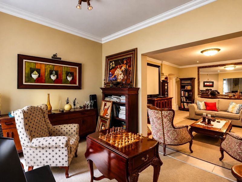 Spacious open-plan living area featuring neutral wall tones, crown molding, and tiled flooring, creating a warm and inviting atmosphere for relaxation and entertaining.
