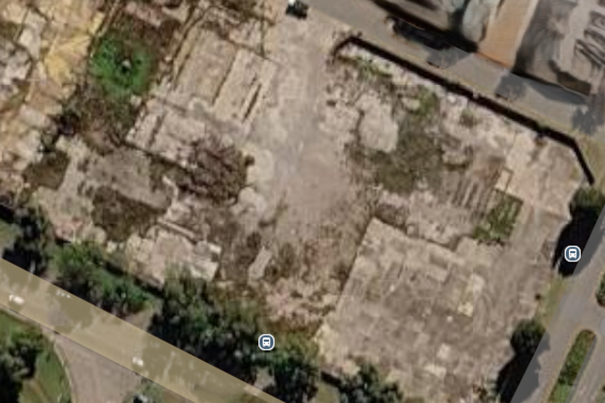 Aerial view of a vacant commercial land plot featuring existing concrete slab foundations and surrounding vegetation.