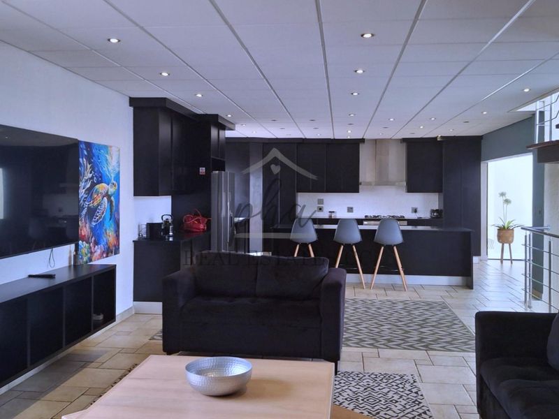 Spacious open-plan living area featuring a modern kitchen with dark cabinetry, a central island, and tiled flooring throughout.
