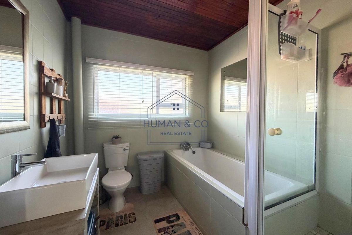 A functional bathroom featuring a built-in bathtub, separate shower enclosure, tiled walls, and a timber-paneled ceiling.