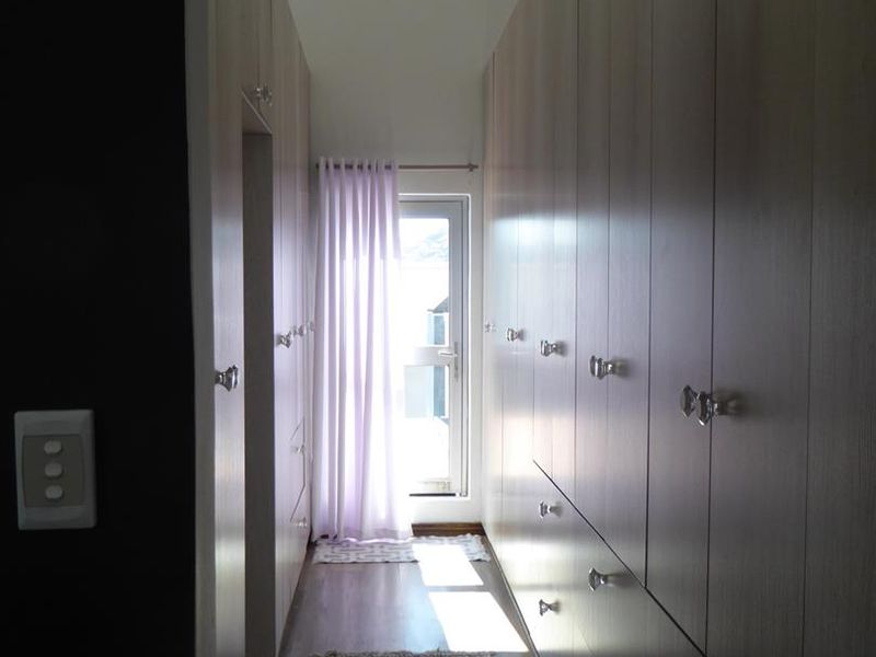 A well-lit hallway featuring extensive built-in cabinetry with modern finishes and direct access to an exterior door.