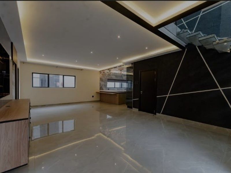 Spacious open-plan living area featuring modern porcelain flooring, recessed ceiling lighting, a striking feature wall, and a contemporary floating staircase with glass balustrade.