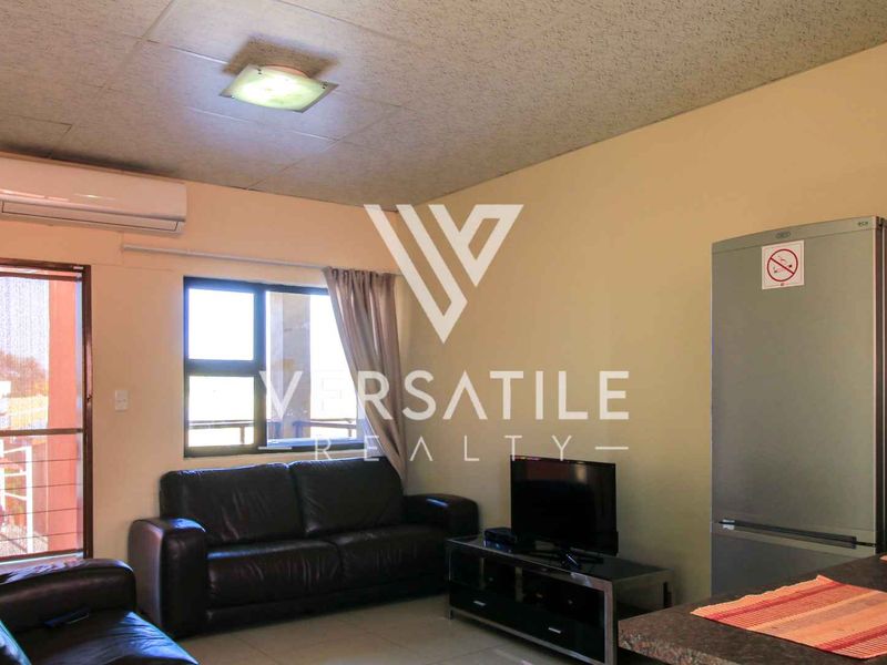 Open plan living area featuring tiled flooring, a split-system air conditioner, and access to an outdoor space via a sliding glass door.