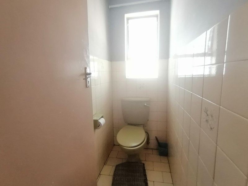 A compact, functional bathroom featuring tiled walls and flooring, equipped with a standard toilet and a window for natural light.