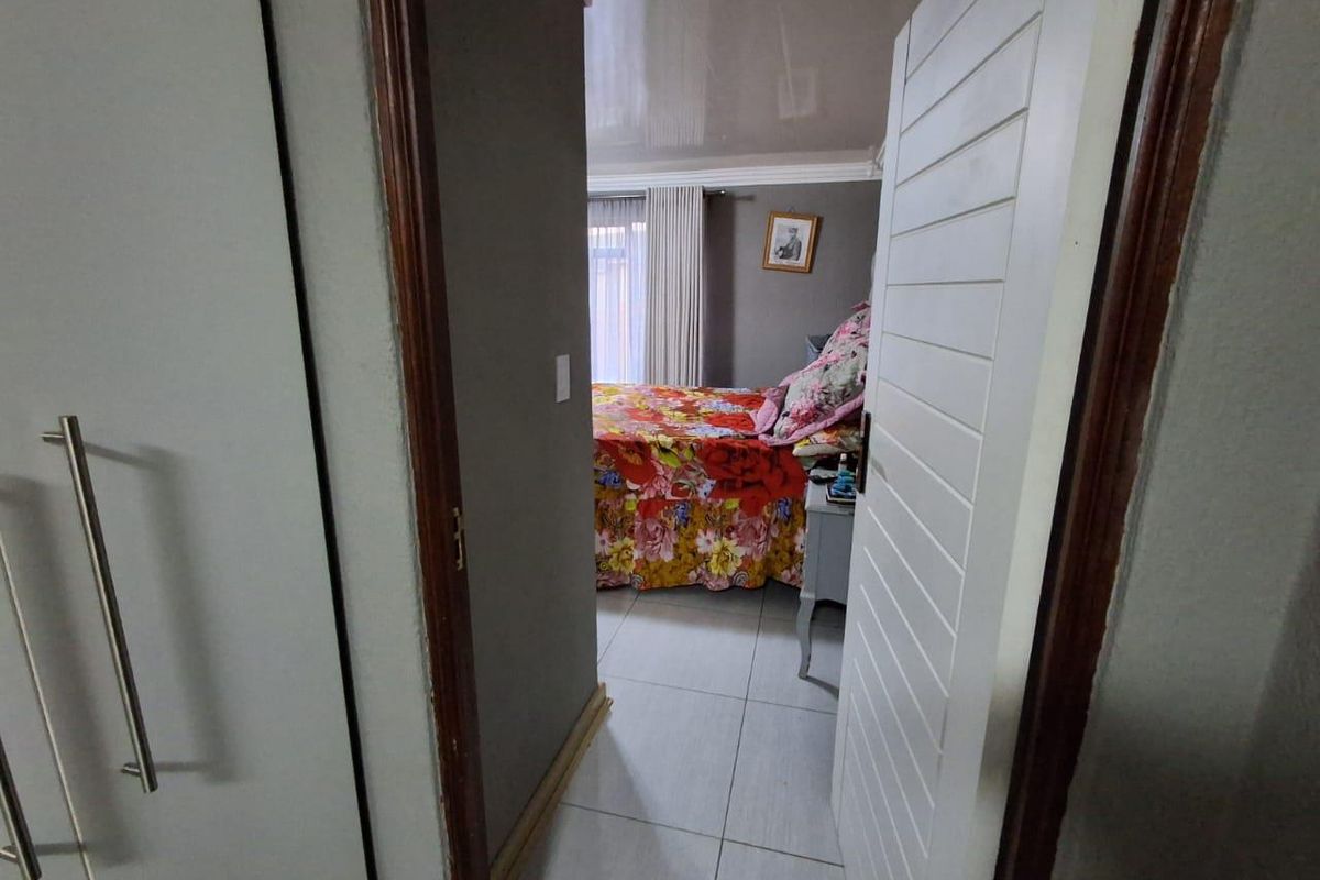 A view through a doorway into a bedroom featuring tiled flooring, built-in cupboards, and a glossy ceiling finish.