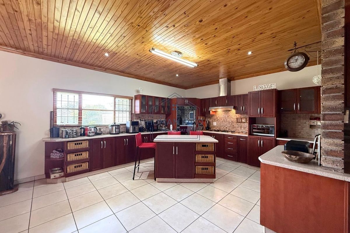 Spacious kitchen featuring dark wood cabinetry, a central island, tiled flooring, and a distinctive timber-paneled ceiling with recessed lighting.