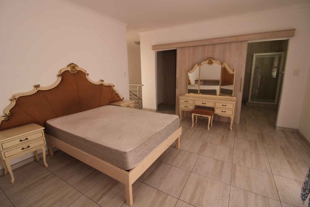 Spacious bedroom featuring light-toned floor tiles, built-in sliding door cupboards, and an en-suite bathroom access.
