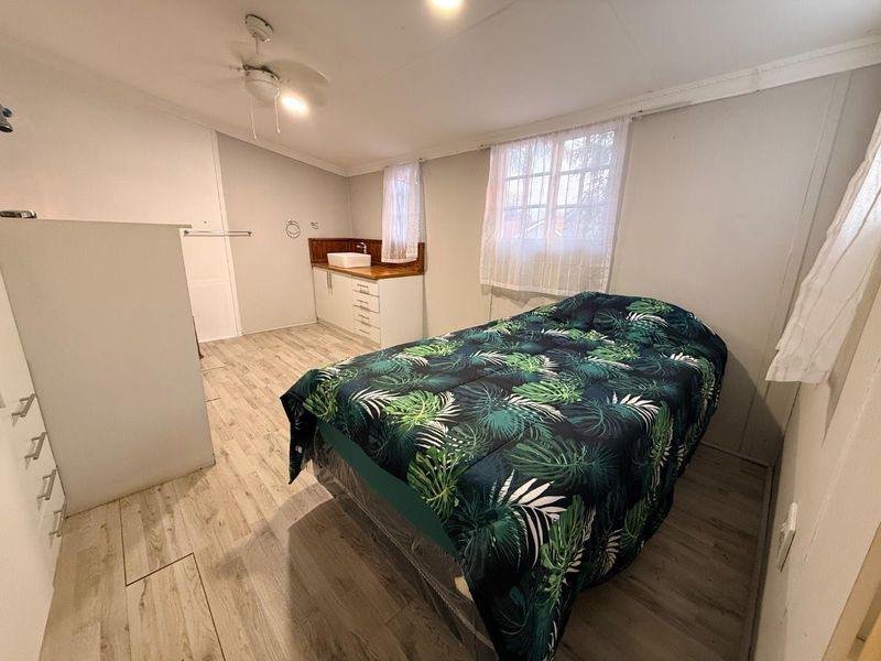 A bedroom featuring laminate flooring, a ceiling fan, and a built-in vanity unit with a vessel sink.