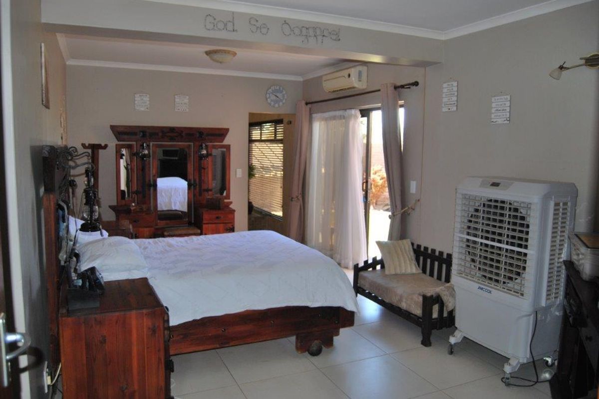 Spacious bedroom featuring tiled flooring, a wall-mounted air conditioning unit, and sliding glass doors providing direct access to the outdoor area.