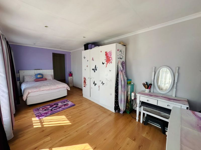 Spacious bedroom featuring hardwood flooring, built-in wardrobe storage, and recessed ceiling lighting.