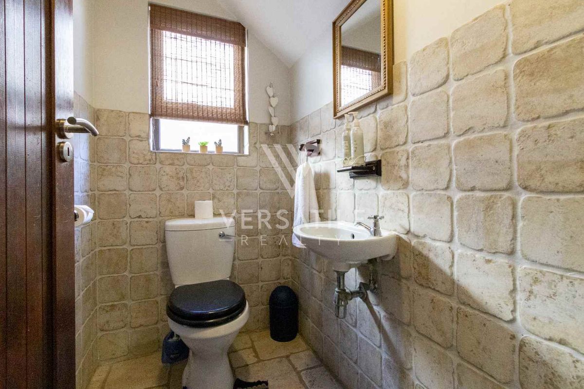 A compact guest bathroom featuring stone-style wall tiling, a wall-mounted basin, and a standard toilet.