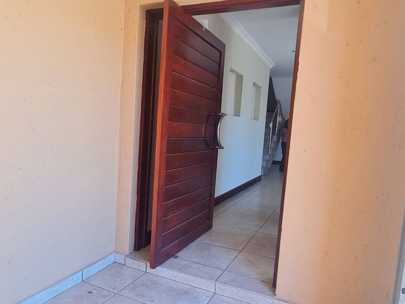 Entrance area featuring a solid wood front door, tiled flooring, and a view into the interior hallway and staircase.
