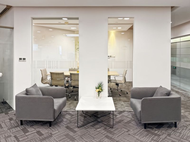 Modern office space featuring glass-partitioned meeting rooms, recessed lighting, and professional carpet flooring in a clean, contemporary corporate environment.