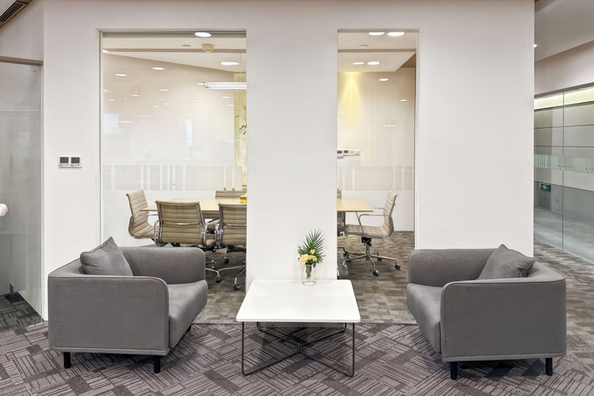 Modern office space featuring glass-partitioned meeting rooms, recessed lighting, and professional carpet flooring in a clean, contemporary corporate environment.