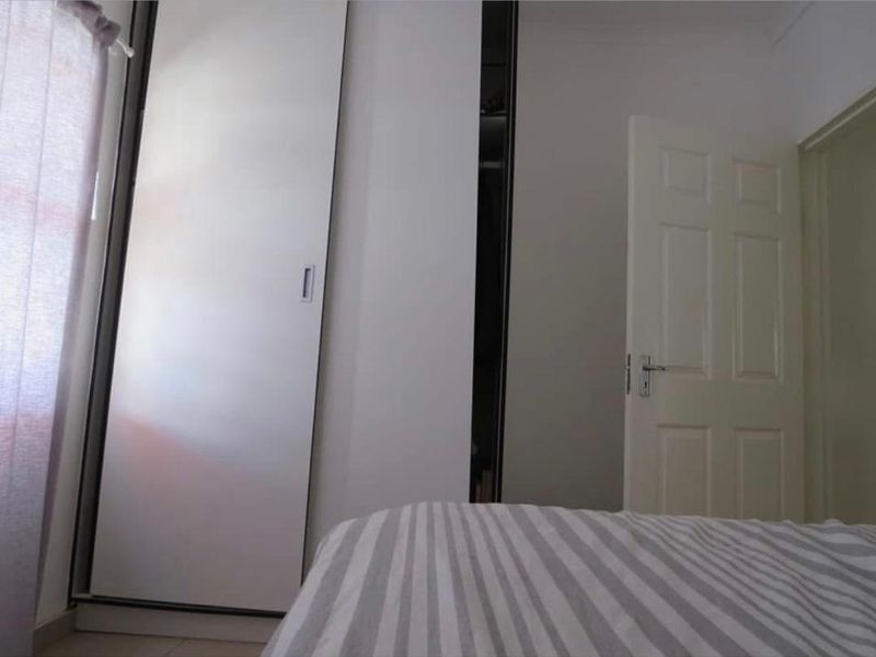 A bedroom featuring a built-in wardrobe with sliding doors and a classic panel door.