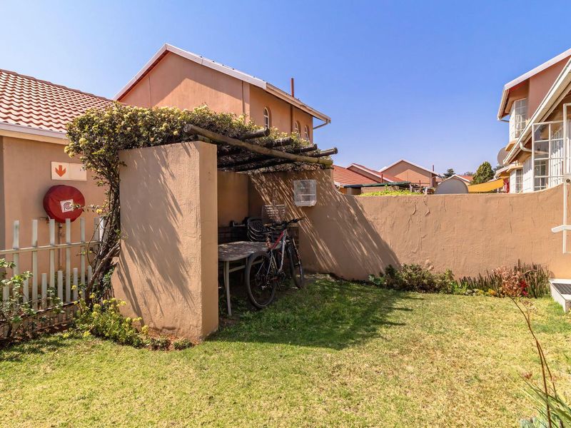 A private rear garden area featuring a small pergola structure, boundary wall, and direct access to the townhouse exterior.
