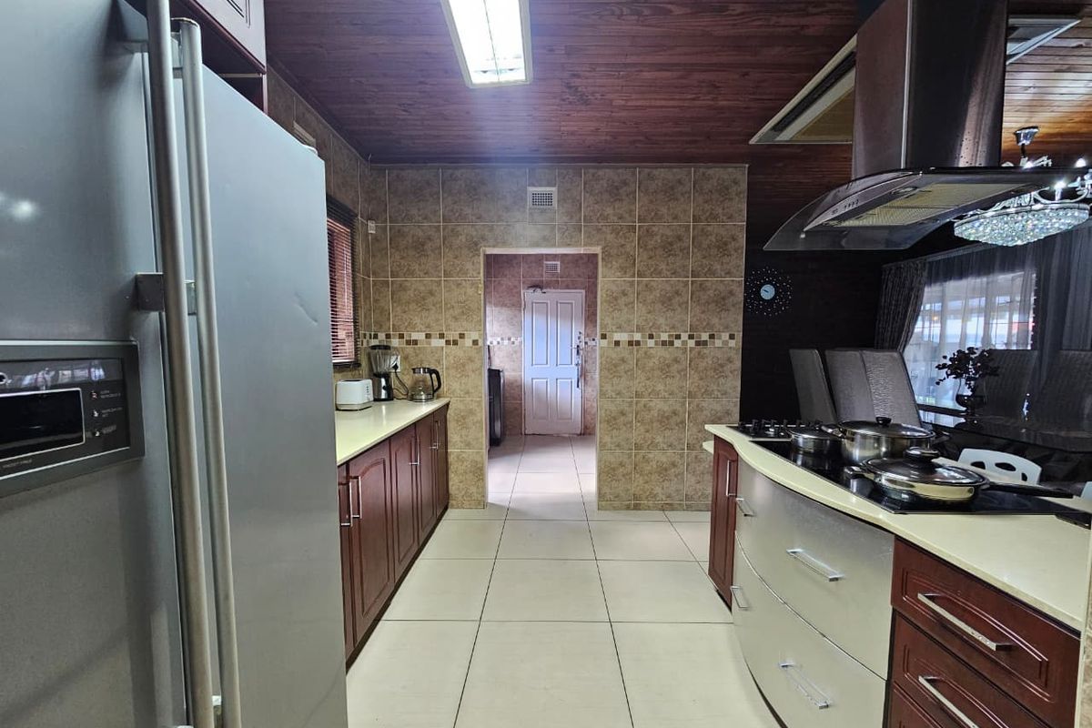 A functional kitchen featuring dark wood cabinetry, tiled walls, a built-in gas hob with extractor fan, and a wooden ceiling finish.