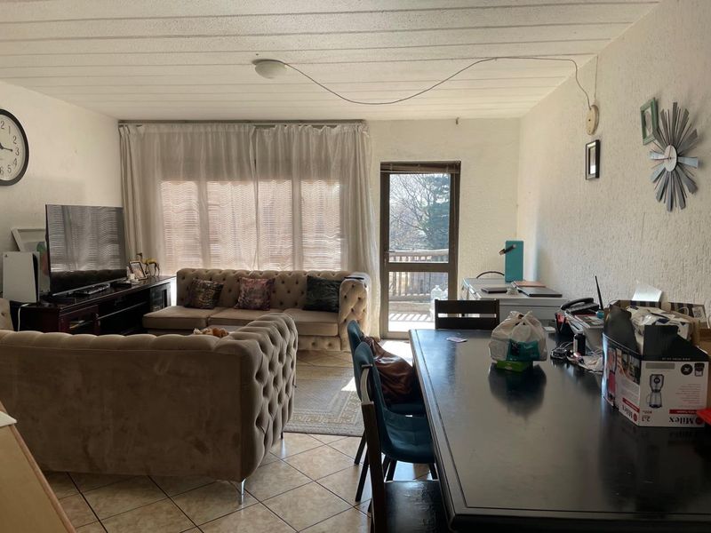 Open-plan living and dining area featuring tiled flooring, textured ceilings, and direct access to an outdoor balcony through a glass door.