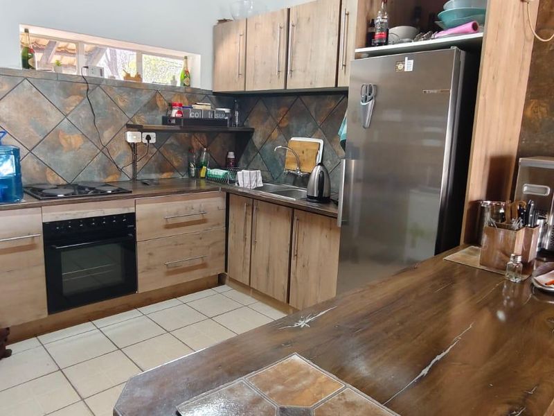 A functional kitchen featuring wood-look cabinetry, a built-in oven and hob, tiled backsplash, and a breakfast counter area.