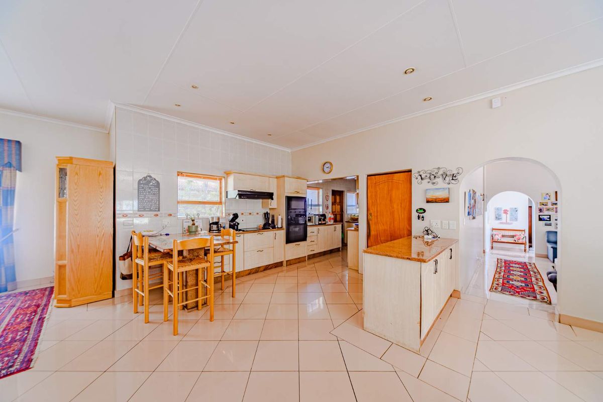Spacious kitchen featuring tiled flooring, built-in cabinetry, a central island, and an integrated oven, leading through an archway to adjacent living areas.