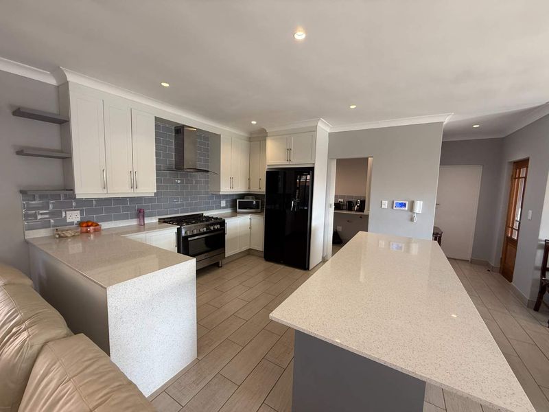 Modern kitchen featuring a large central island, quartz countertops, subway tile backsplash, gas stove, and ample built-in cabinetry with recessed lighting.
