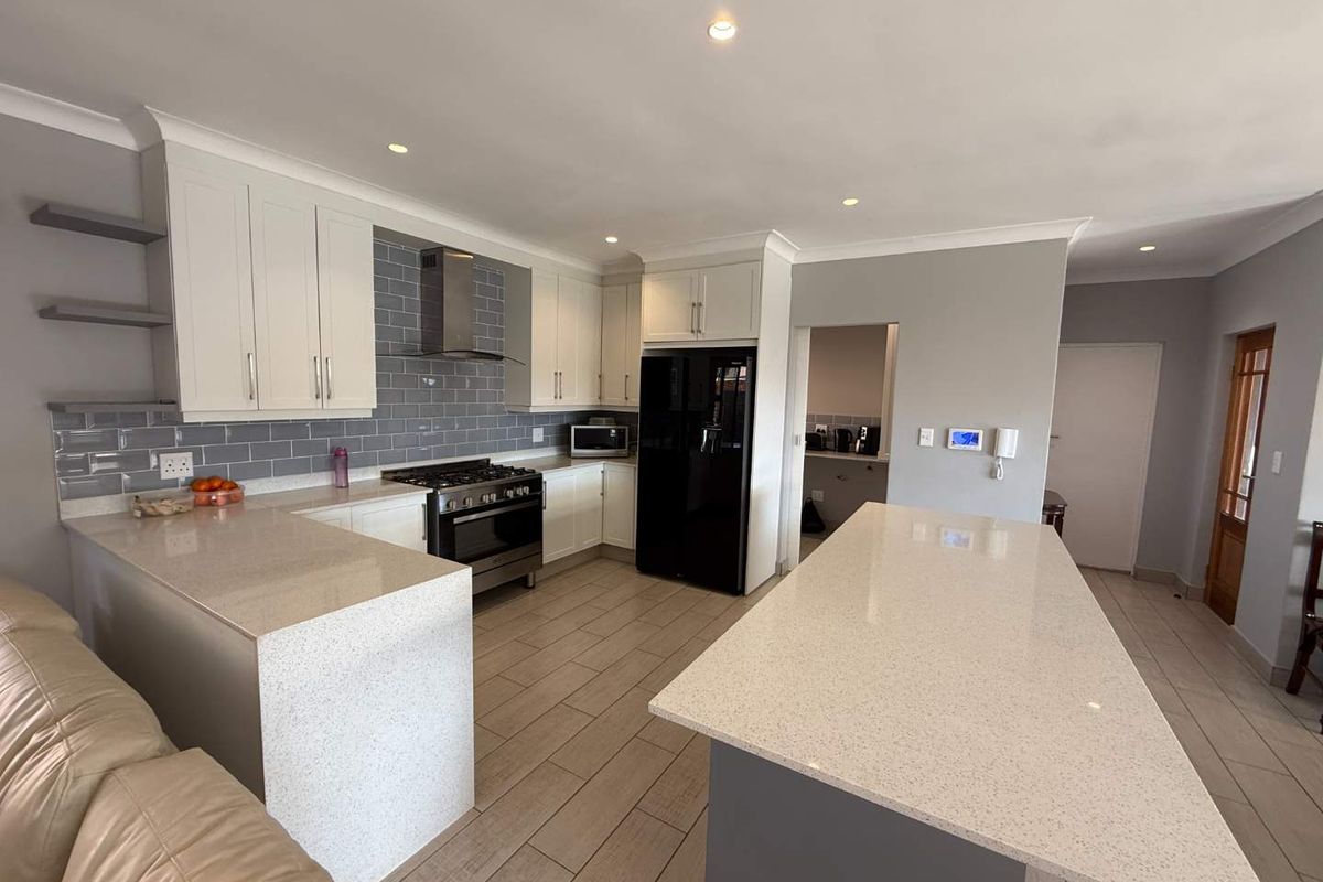 Modern kitchen featuring a large central island, quartz countertops, subway tile backsplash, gas stove, and ample built-in cabinetry with recessed lighting.