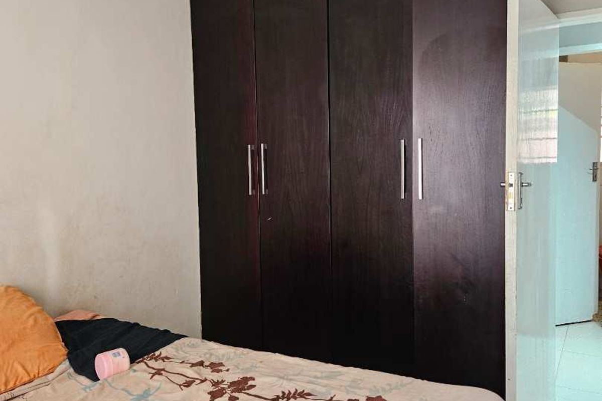 A bedroom featuring dark wood built-in cupboards, tiled flooring, and crown molding detail.