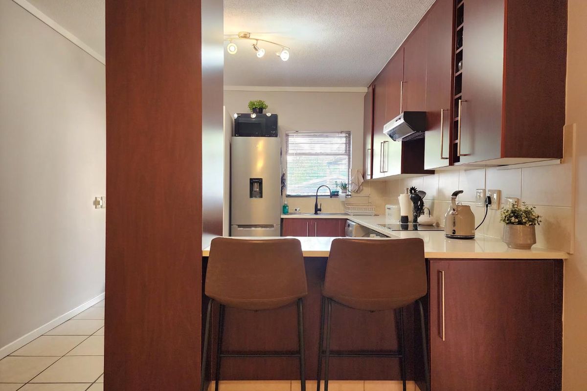 A functional kitchen featuring dark wood cabinetry, a breakfast bar, tiled backsplash, and integrated appliances, offering a practical layout for daily use.