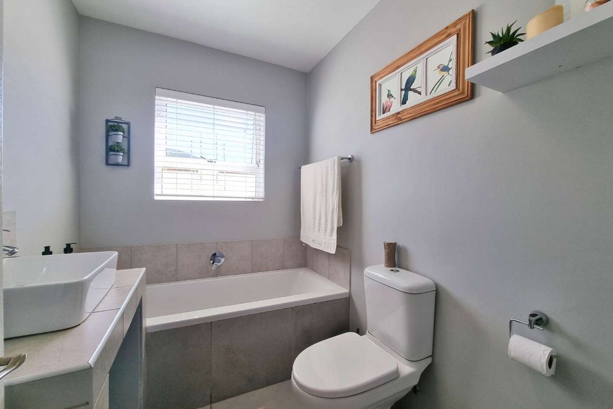A clean and functional bathroom featuring a built-in bathtub, a modern vessel sink vanity, and a standard toilet.