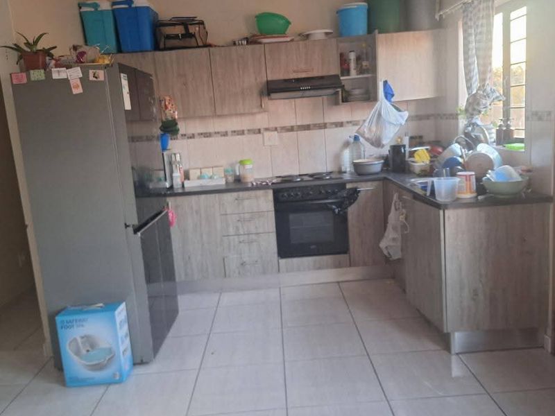 A functional kitchen featuring wood-look cabinetry, built-in oven and hob, tiled backsplash, and tiled flooring.