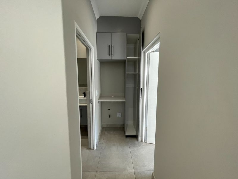A clean, modern laundry nook featuring built-in cabinetry, tiled flooring, and dedicated plumbing and electrical connections for appliances.