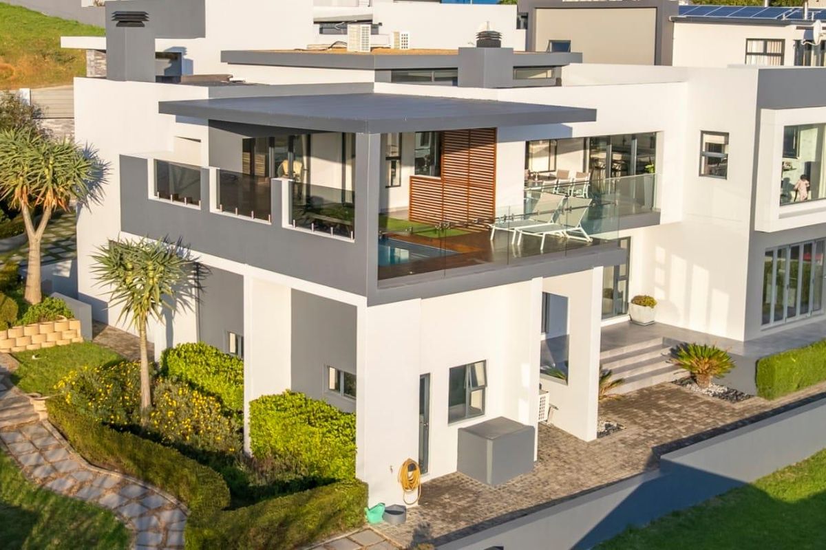 Aerial view of a modern multi-level residential property featuring a balcony with a small plunge pool, landscaped garden, and contemporary architectural design.