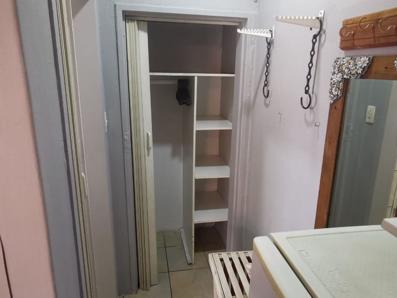 A small utility or storage area featuring built-in shelving and a folding door, providing functional storage space within the cottage.