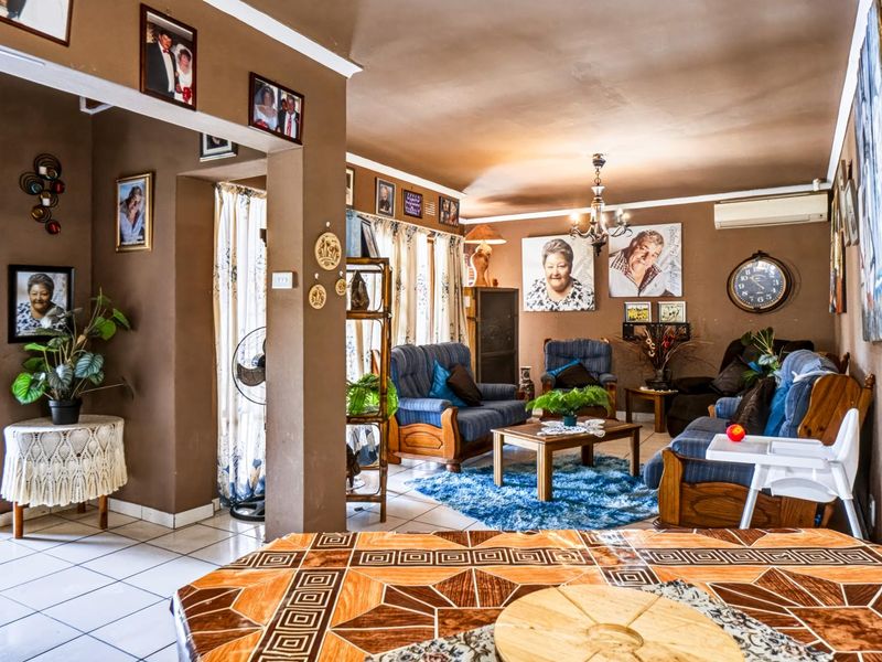 A spacious living room featuring tiled flooring, a split-system air conditioner, and an open-plan layout with a connecting archway.