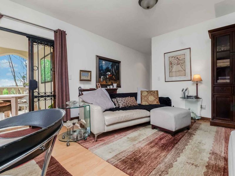 A comfortable living room featuring laminate flooring and a sliding glass door that opens onto a private balcony.