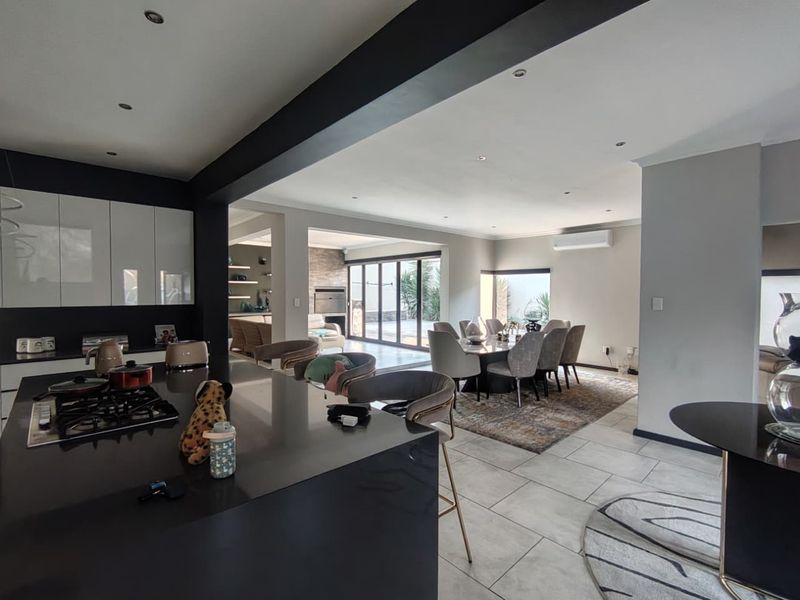 Spacious open-plan living area featuring a modern kitchen with a central island, gas hob, and seamless flow to the outdoor patio through stacking doors.