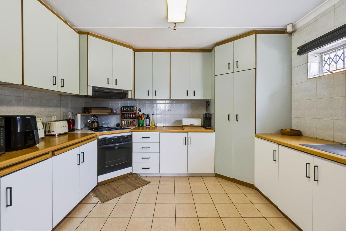 A functional kitchen featuring white built-in cabinetry, laminate countertops, a gas hob, and tiled flooring with a neutral backsplash.