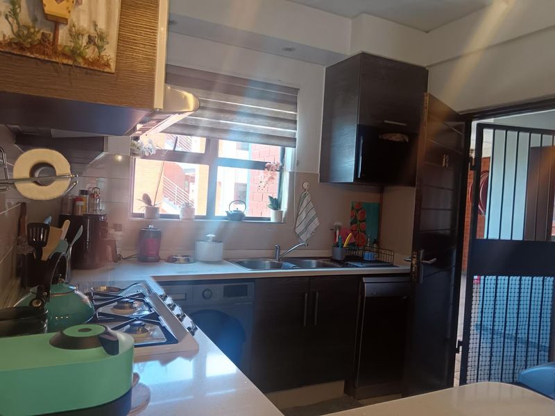 Compact kitchen featuring dark wood cabinetry, stone countertops, a gas hob with extractor, and a double sink with a window view.
