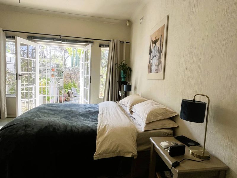 A bedroom featuring textured walls and double french doors providing direct access to a private outdoor patio area.
