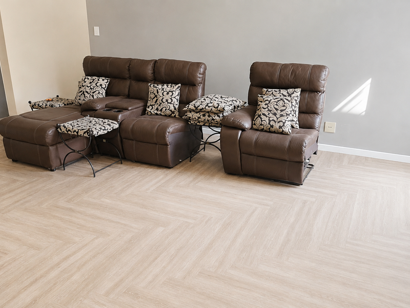 A bright living room featuring modern light-toned herringbone flooring and neutral wall finishes, providing a clean and contemporary foundation for the space.